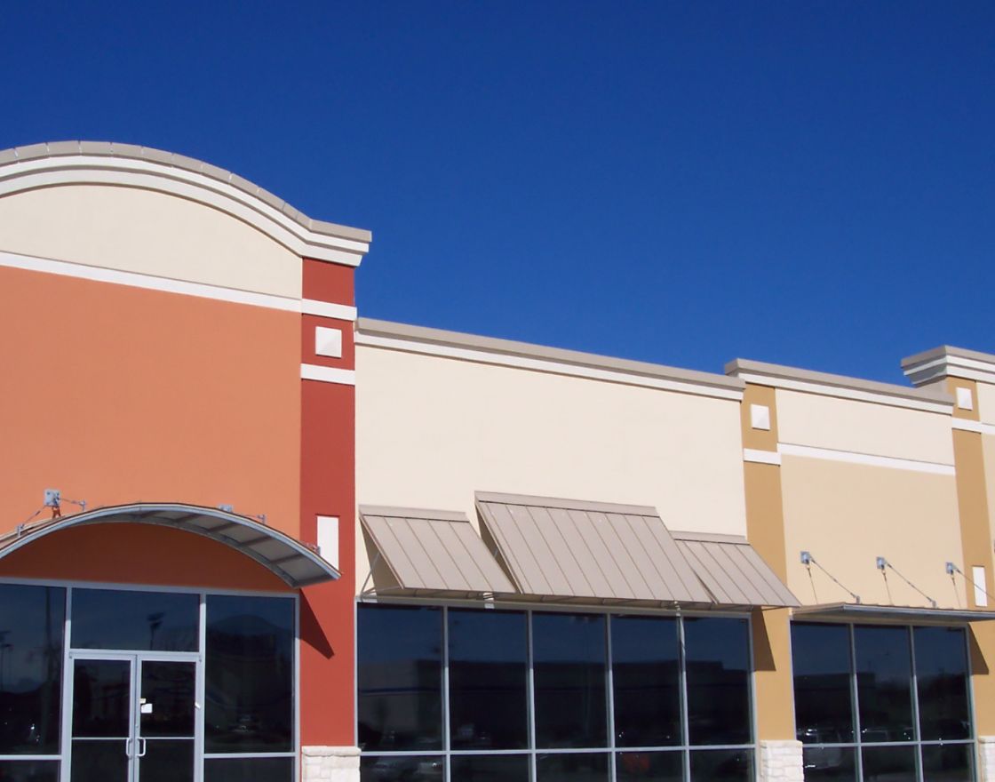 Retail centre with storefront awnings under a clear blue sky